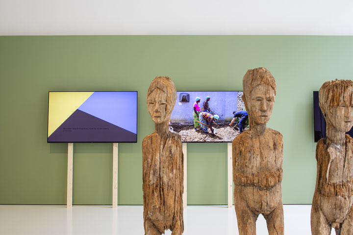 Ocaina, Witoto: Holzstatuen foonhunraaga, ca. 1963 aus Südamerika;  Im Hintergrund: Uriel Orlow, <i>Learning from Artemisia</i>, Three-channel video, 2019 © Museum der Kulturen Basel, Omar Lemke